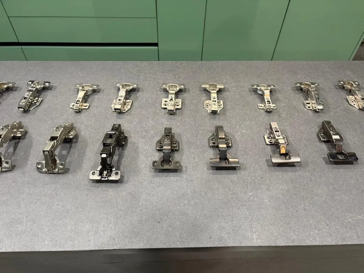 Row of concealed soft-close cabinet hinges on a showroom counter